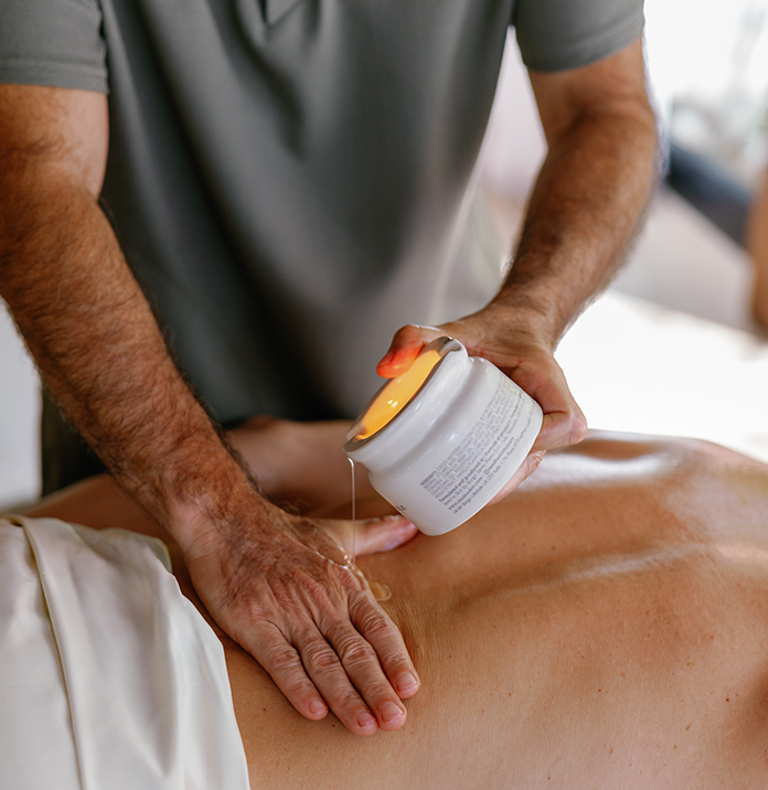 a man pouring a cream onto a person's back