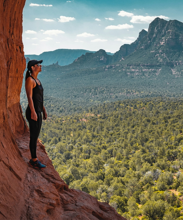 a woman standing on a cliff looking at a valley
