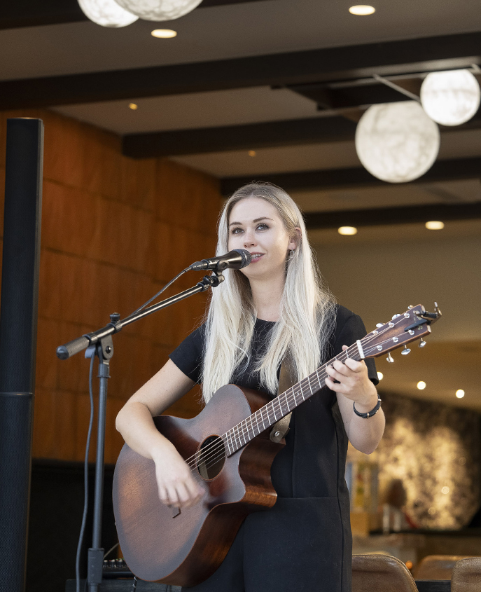 a woman playing guitar and singing into a microphone