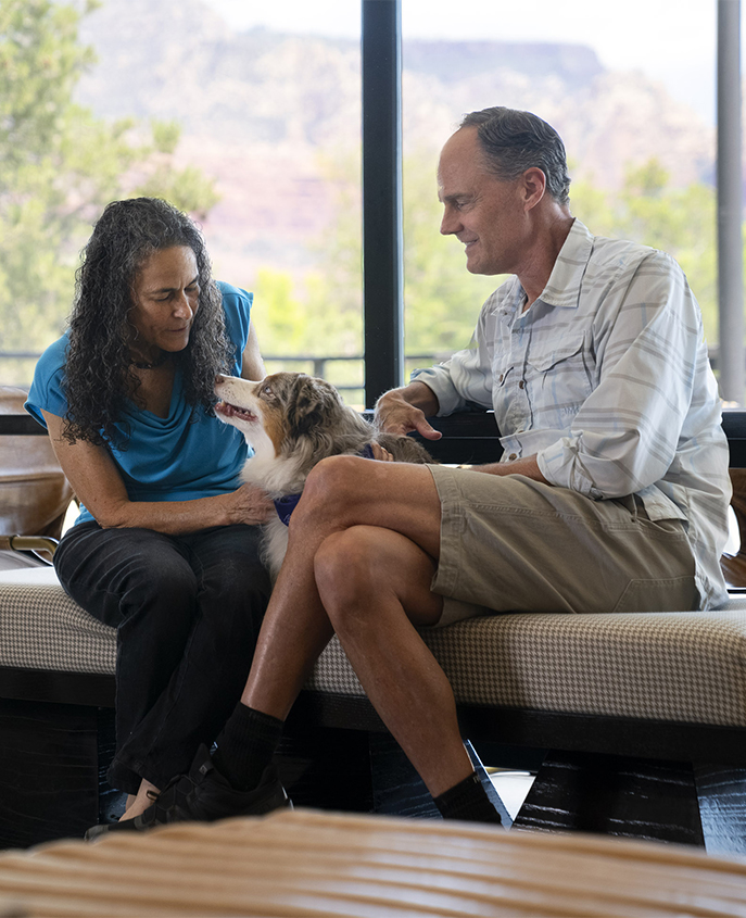 a man and woman sitting on a bench with a dog