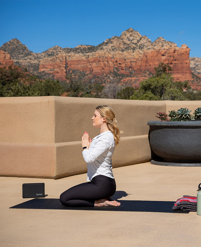 a woman sitting on a yoga mat with her hands together