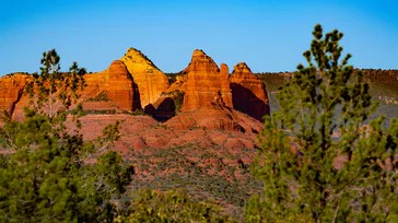 a red rock formation with trees in the background