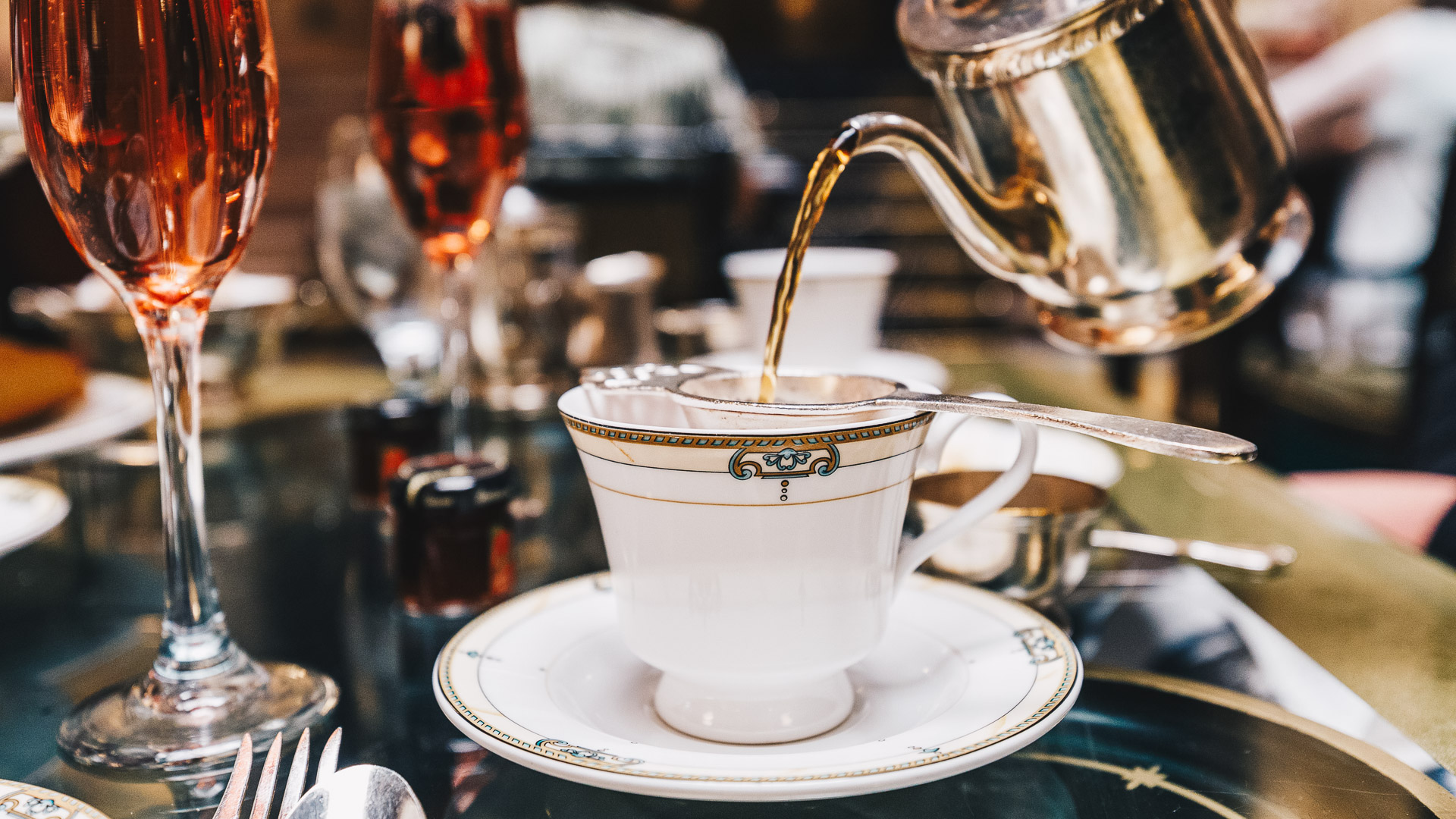 a teacup and saucer with a teapot pouring liquid into it