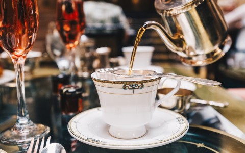 a teacup and saucer with a teapot pouring liquid into it