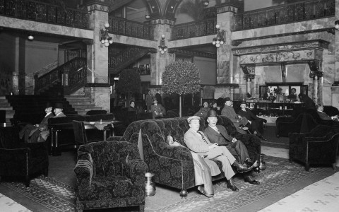 a group of men sitting on a couch in a large room