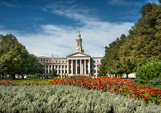 a large white building with columns and a tower with a tower and a garden with flowers