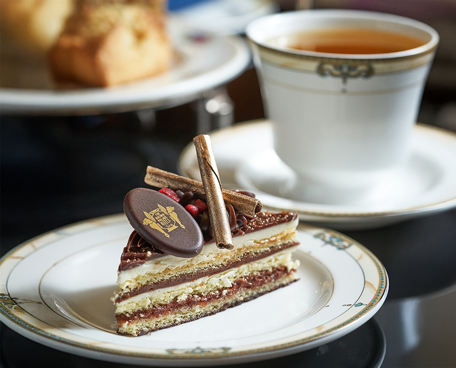 a piece of cake on a plate next to a cup of tea