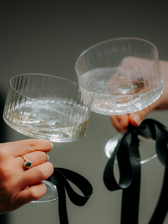 a pair of hands holding glasses with black ribbons