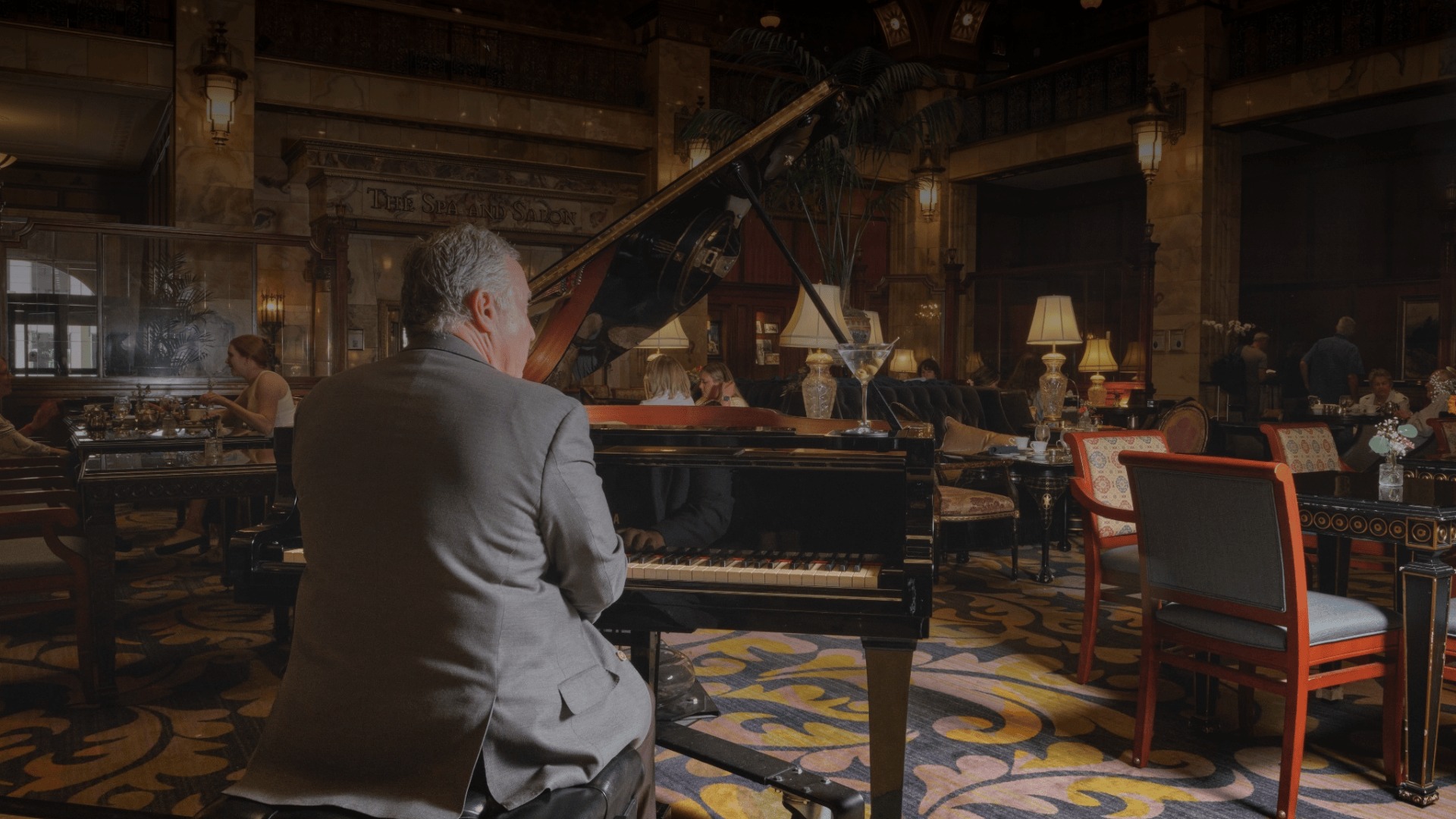 a man playing a piano in a room with tables and chairs