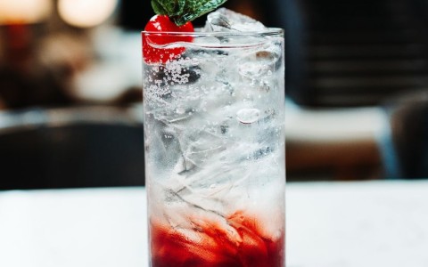 a glass with a drink and a cherry on top