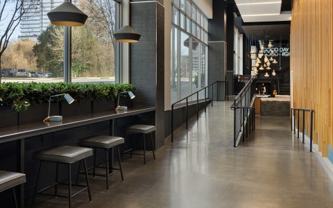 a long hallway with a row of stools and a window