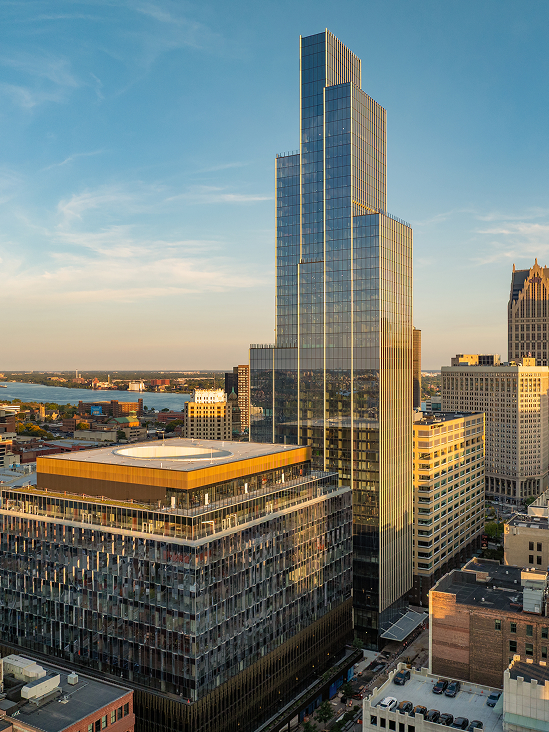 a tall glass building with a river in the background