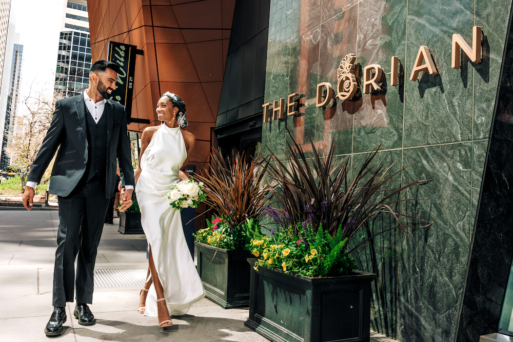 a man and woman in a white dress walking down a sidewalk