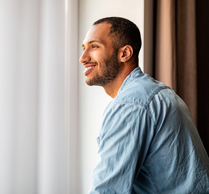 a man smiling looking out a window