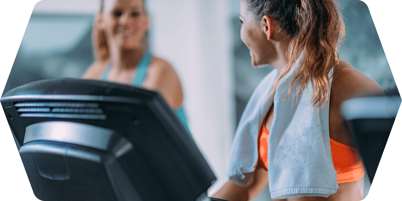 a woman smiling at another woman on a treadmill