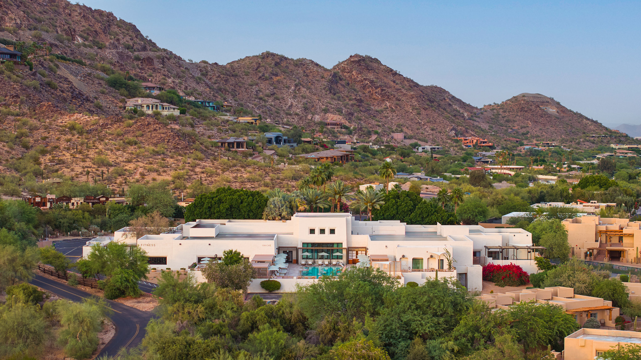 a white building with trees and mountains in the background