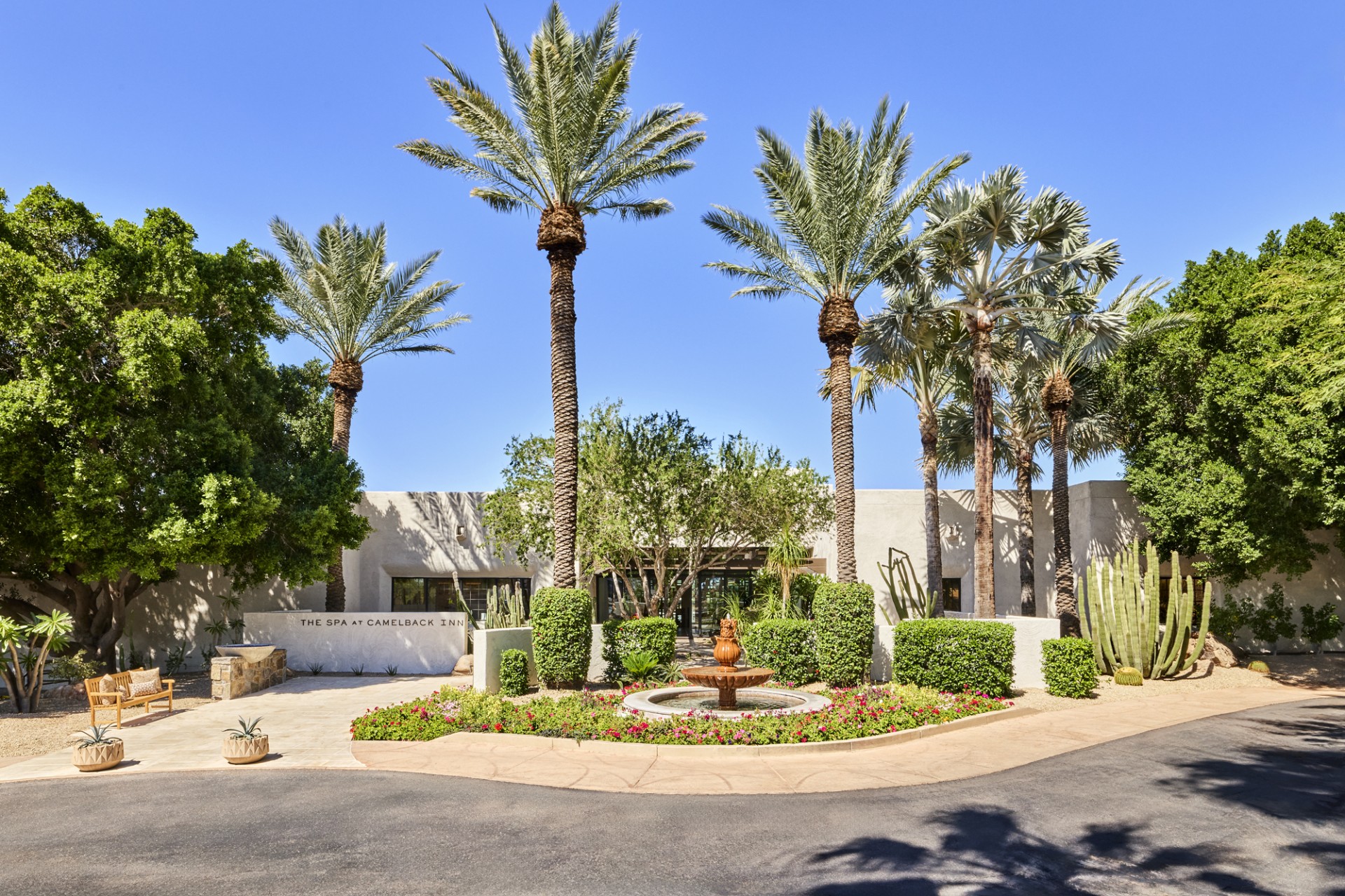 a fountain in front of a building with palm trees