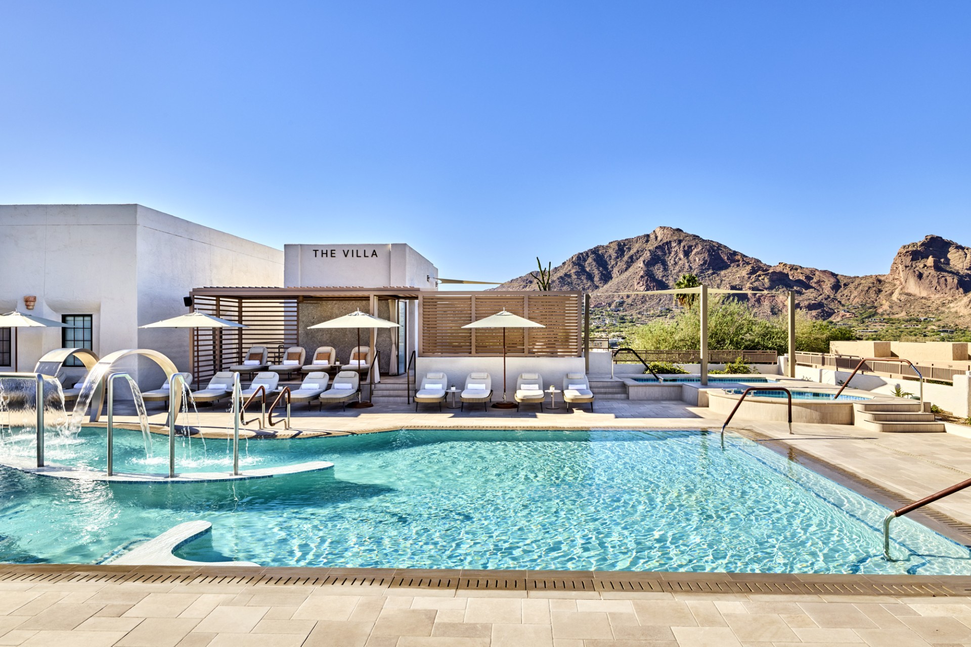 a pool with chairs and umbrellas in front of a building