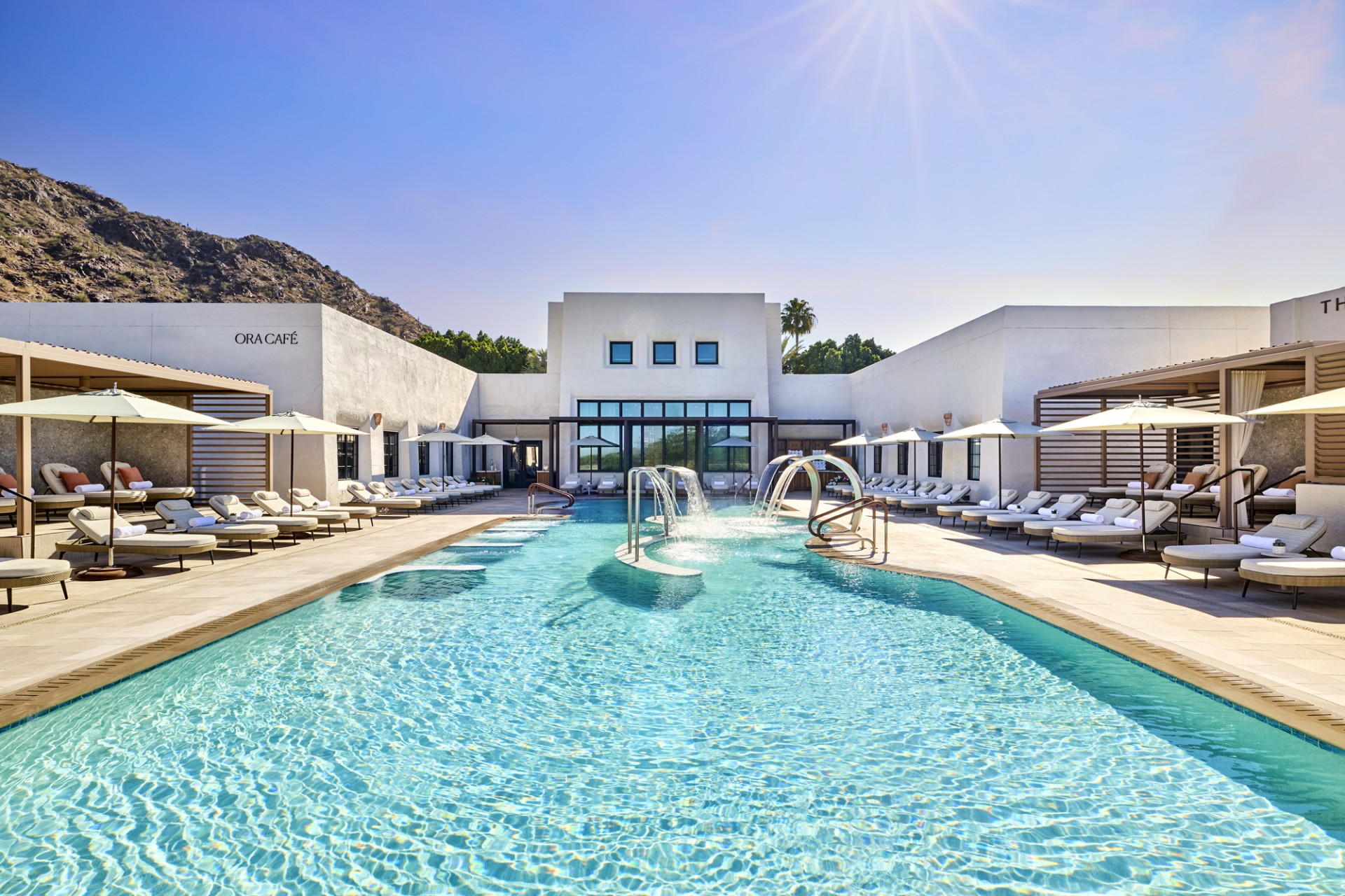a swimming pool with a slide and a building with a mountain in the background