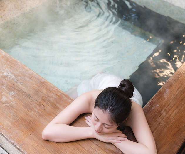 a woman lying on a wood surface in a hot tub