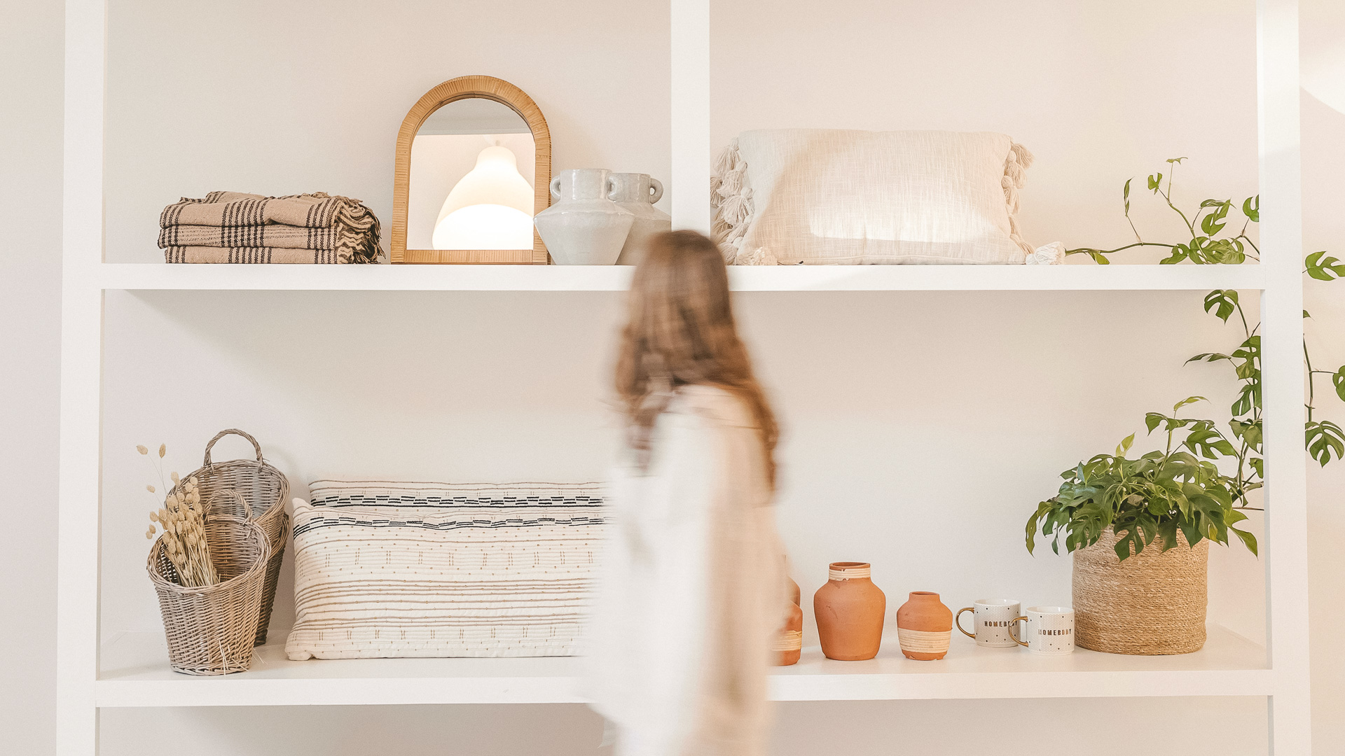 a woman standing in front of shelves with objects on them