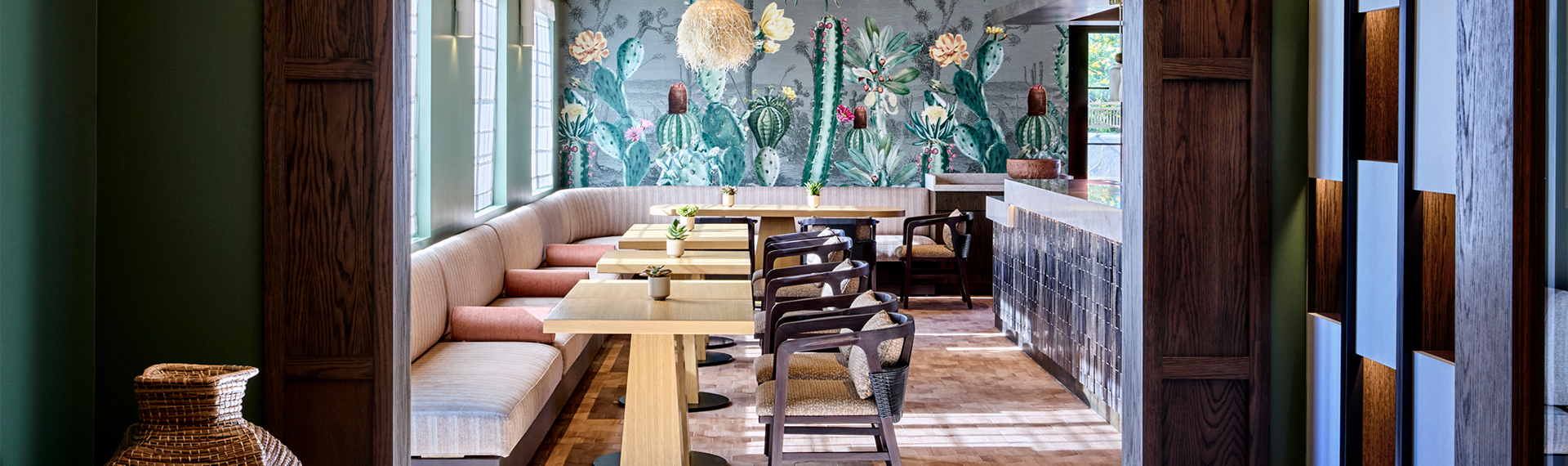 a room with tables and chairs and a wall with cactus wallpaper