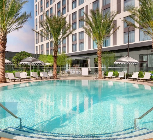 a pool with palm trees and umbrellas in front of a building