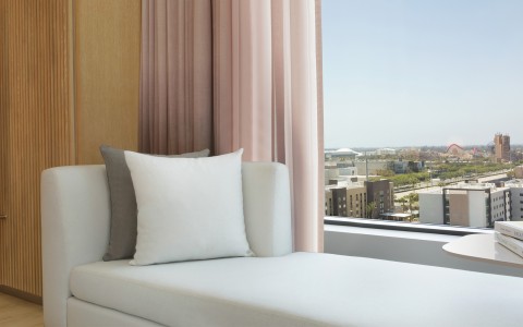 a couch with pillows in a room with pink curtains