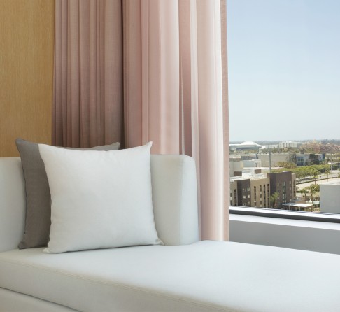 a couch with pillows in a room with pink curtains
