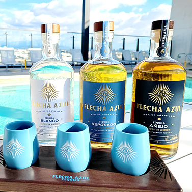 a group of bottles of alcohol next to blue cups