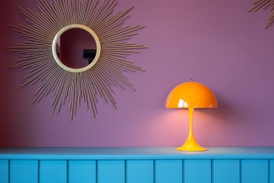 a yellow lamp on a shelf next to a mirror