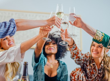 a group of women clinking wine glasses