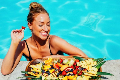 a woman in a swimsuit eating a fruit platter