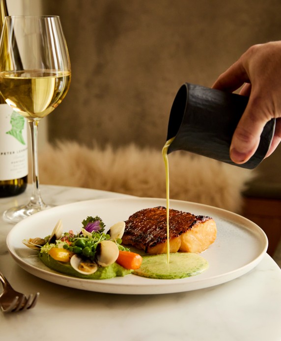 a person pouring liquid onto a plate of food