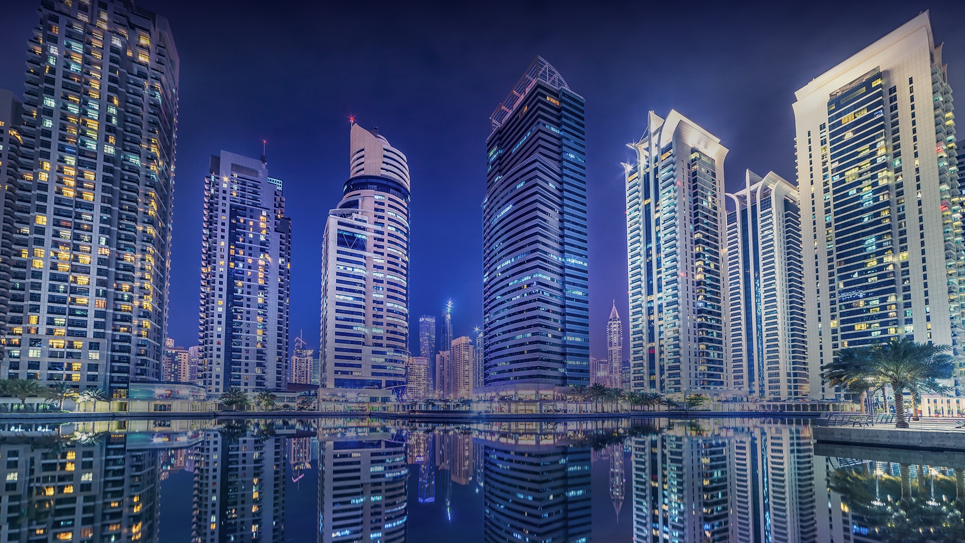 a city skyline with many tall buildings reflecting in water in dubai